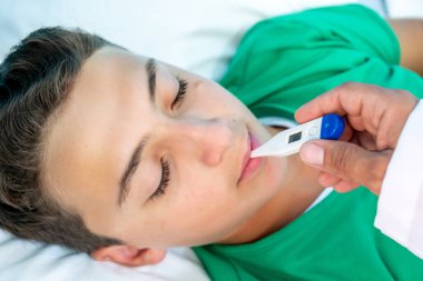 Doktor yüksek ateşi olup olmadığını kontrol ediyor.