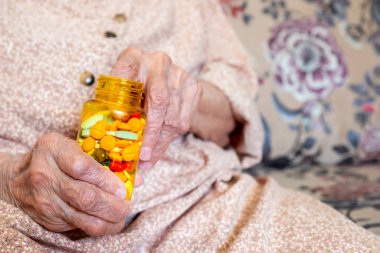 Yaşlı kadın ilaçlarını elinde tutuyor.