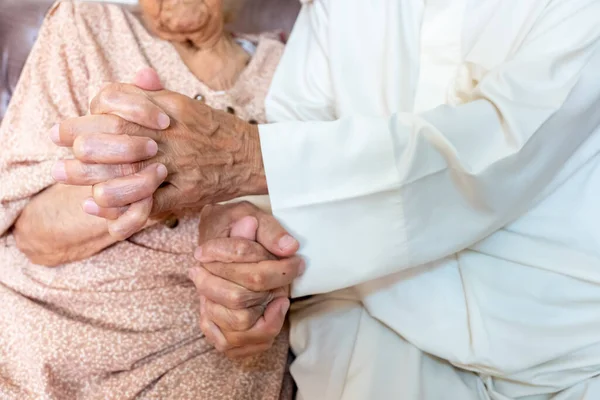 Two old people holding each other hand