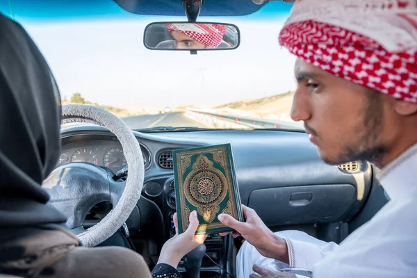 Two arabic people holding holy book in their hands