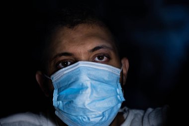 Karanlıktaki adam nefesini dumandan ve kirlilikten korumak için koruyucu maske takıyor.