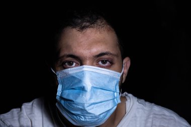 Karanlıktaki adam nefesini dumandan ve kirlilikten korumak için koruyucu maske takıyor.