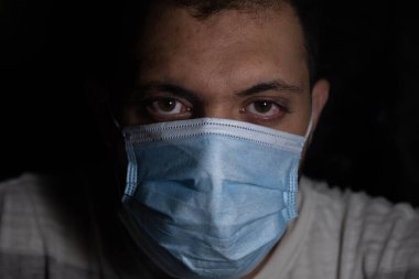 Karanlıktaki adam nefesini dumandan ve kirlilikten korumak için koruyucu maske takıyor.