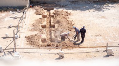 İşçiler kompresör kullanılarak mahalledeki tasarıma göre yeni bir evin temellerini kazıyorlar.