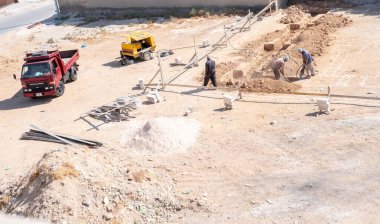 İşçiler kompresör kullanılarak mahalledeki tasarıma göre yeni bir evin temellerini kazıyorlar.