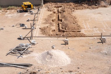 İşçiler kompresör kullanılarak mahalledeki tasarıma göre yeni bir evin temellerini kazıyorlar.