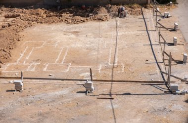 İşçiler kompresör kullanılarak mahalledeki tasarıma göre yeni bir evin temellerini kazıyorlar.