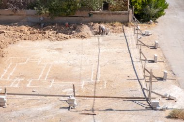 İşçiler kompresör kullanılarak mahalledeki tasarıma göre yeni bir evin temellerini kazıyorlar.