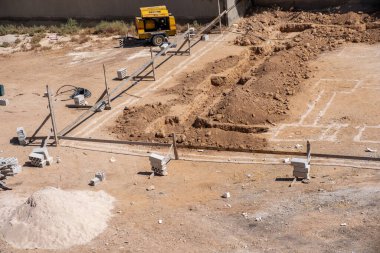 İşçiler kompresör kullanılarak mahalledeki tasarıma göre yeni bir evin temellerini kazıyorlar.