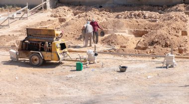 İşçiler kompresör kullanılarak mahalledeki tasarıma göre yeni bir evin temellerini kazıyorlar.