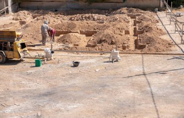 İşçiler kompresör kullanılarak mahalledeki tasarıma göre yeni bir evin temellerini kazıyorlar.