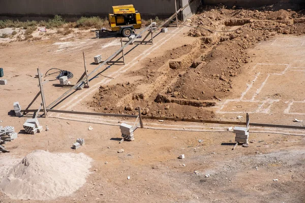 İşçiler kompresör kullanılarak mahalledeki tasarıma göre yeni bir evin temellerini kazıyorlar.