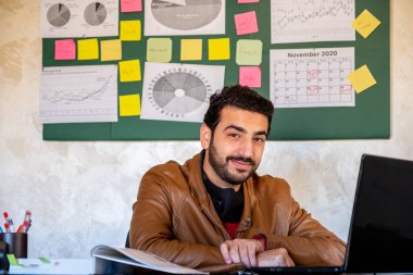 Genç adam ofisinden neşeli bir gülümseme ve şevkle çalışıyor.