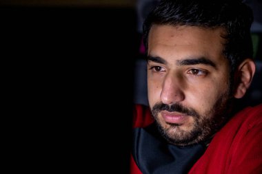 Geç saatlere kadar ofisinden uzakta, yüzünde ciddi bir ifadeyle projesinde çalışan genç bir adam.