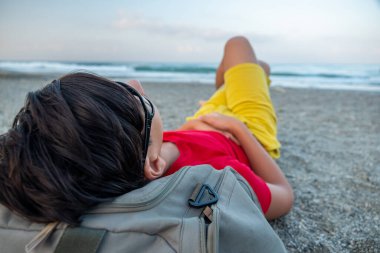 Genç adam kumların üzerinde yatıyor.