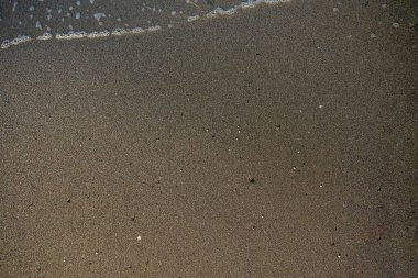 Üzerinde kum ve küçük dalgalar.