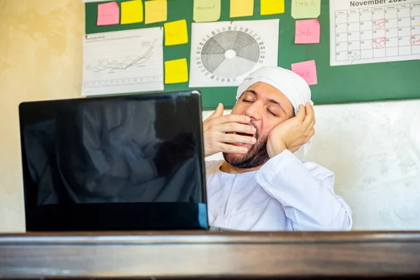 arabian man feeling sleepy while working from home