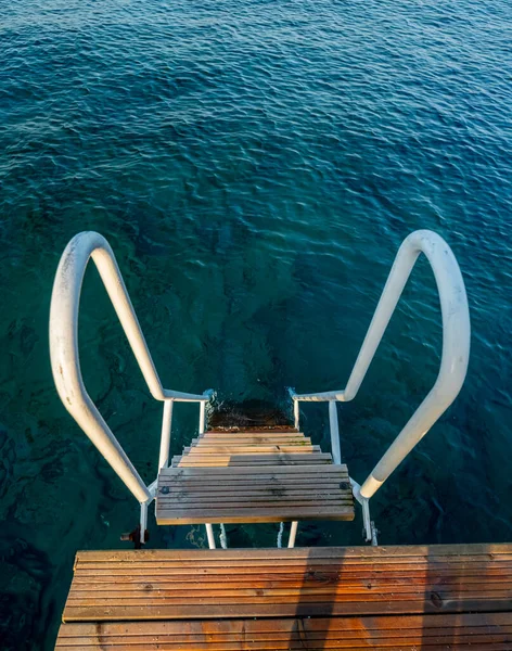 Old wood stairs on a pier and a beautiful water