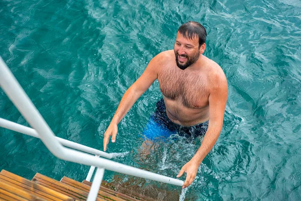 Man climbing up the stairs after finishing his jump inside the water