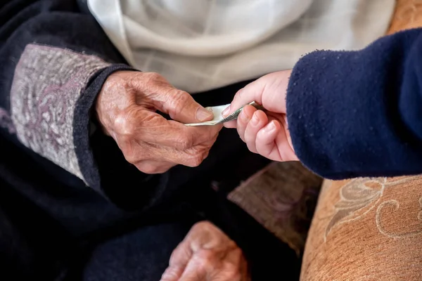 アラビア語のEidの間に彼女の孫にお金を与える老婦人の手 ストック写真