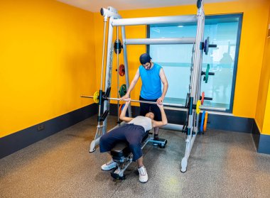 Spor salonunda dayanıklılığını arttırmak için çapraz makine kullanan Arap adam eğitimi.