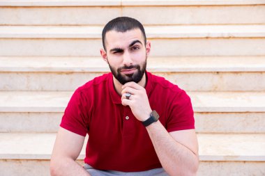 Kendine güveni yüksek bir şekilde merdivenlerde oturan Arap adam.