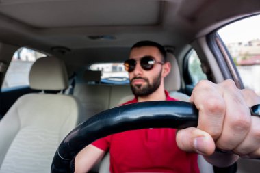 Arap adam gülümseyerek ve kendinden emin bir şekilde arabasını sürüyor.