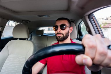 Arap adam gülümseyerek ve kendinden emin bir şekilde arabasını sürüyor.