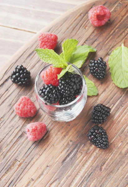 Baies noires et framboises dans une tasse en verre — Photo