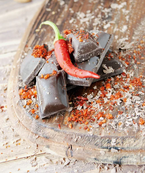 Kousky čokolády s chilli papričkami na dřevěný stůl — Stock fotografie