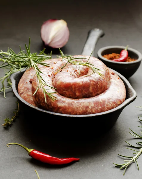 Rå nötkött korv på en gjutjärn stekpanna, selektiv inriktning — Stockfoto