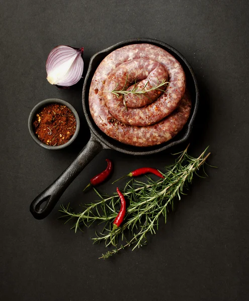 Salsichas de carne crua em uma panela de ferro fundido, foco seletivo — Fotografia de Stock