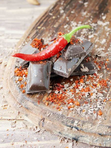 Kousky čokolády s chilli papričkami na dřevěný stůl — Stock fotografie