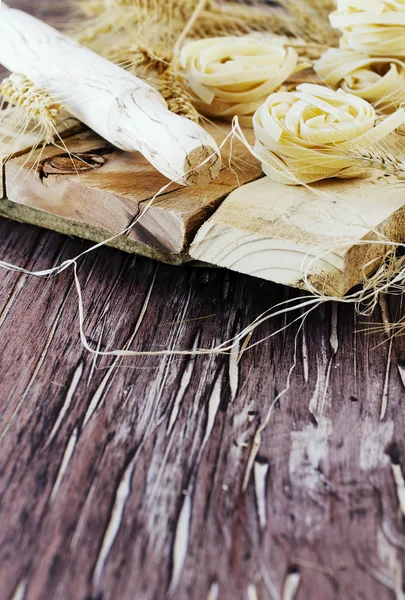 Pâtes alimentaires non cuites avec farine sur la table, mise au point sélective — Photo