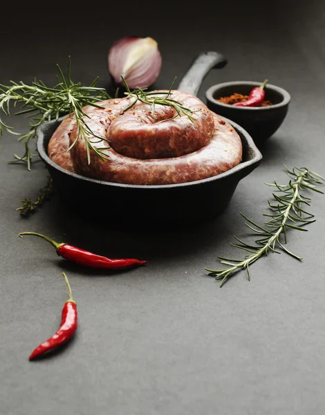 Rå nötkött korv på en gjutjärn stekpanna, selektiv inriktning — Stockfoto