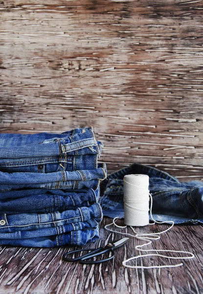 Stack of jeans lying on a wooden table — Stock Photo, Image