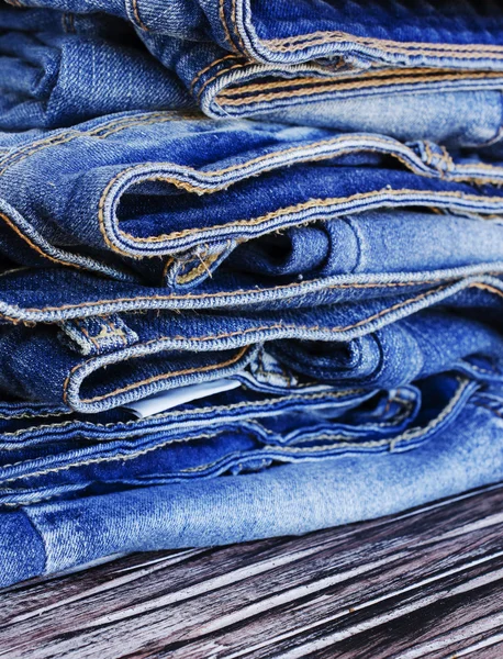 Stapel Jeans auf einem Holztisch liegend — Stockfoto