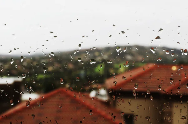 yağmur ile Cam evler arka plan üzerinde kırmızı çatılar düşer.