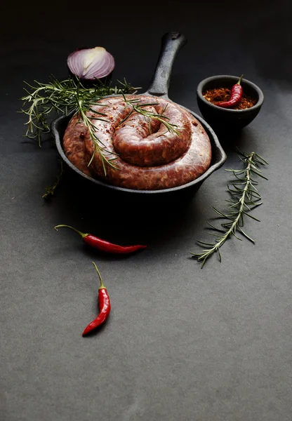 Salsichas de carne crua em uma panela de ferro fundido, foco seletivo — Fotografia de Stock