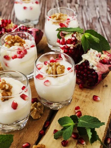 Yogurt dessert with walnuts and pomegranate selective focus — Stock Photo, Image