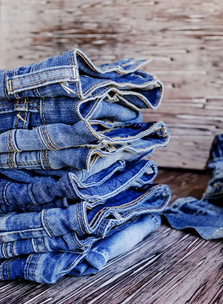 Stapel Jeans auf einem Holztisch liegend — Stockfoto