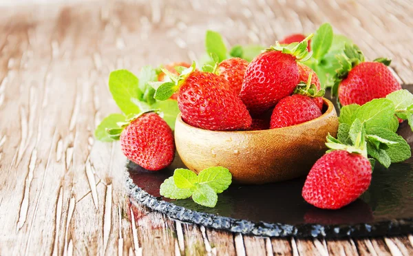 Ripe red raspberries and strawberries in wooden bowl, selective focus — Stock Photo, Image