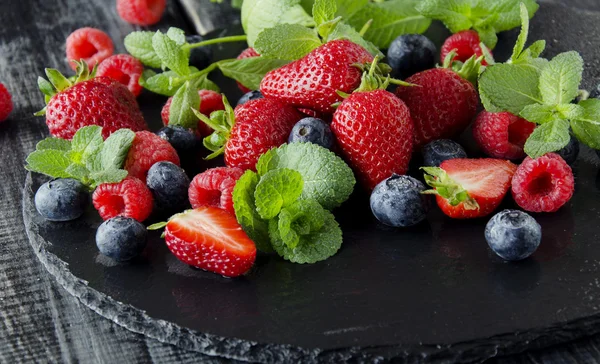 Fresh strawberries, raspberries and blueberries on a black background — Stock Photo, Image