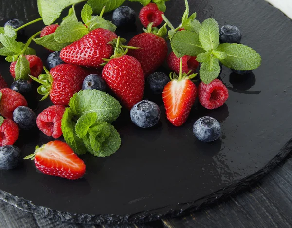 Fresh strawberries, raspberries and blueberries on a black background — Stock Photo, Image