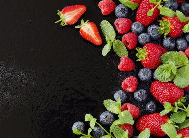 taze çilek, ahududu ve siyah bir arka plan üzerinde yaban mersini