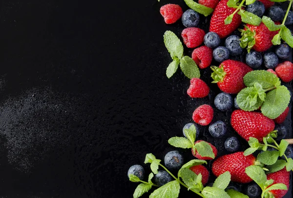 taze çilek, ahududu ve siyah bir arka plan üzerinde yaban mersini