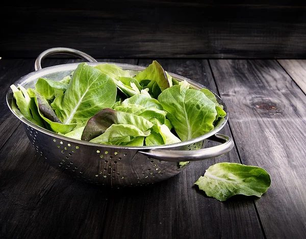Panela com uma salada verde em tábuas de madeira — Fotografia de Stock