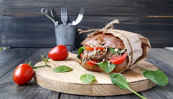 Hamburger siyah ekmek ve masada domates ile