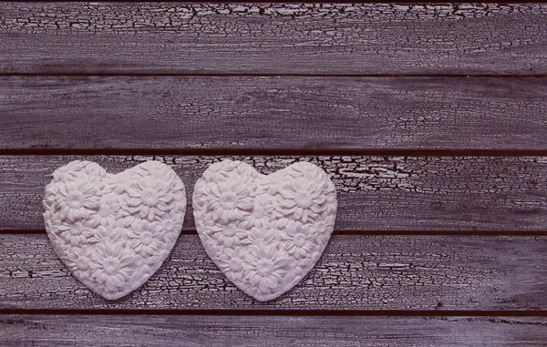 Twee witte harten op leeftijd houten achtergrond — Stockfoto