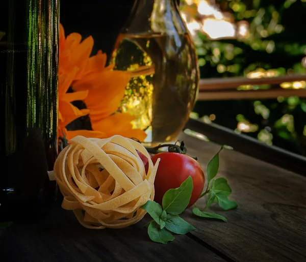 Sunflowers, pasta, tomatoes, basil and a bottle of oil — Stock Photo, Image